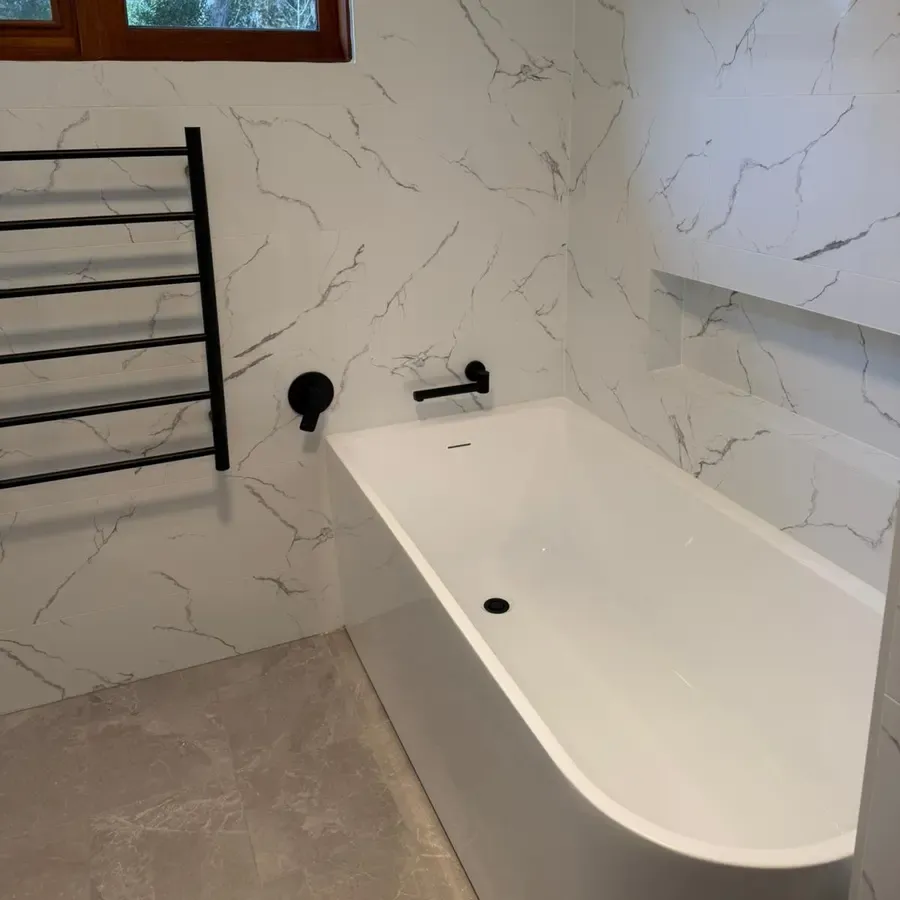 The new bath with a matte black wall mixer and a black heated towel rail in the renovated Katoomba bathroom