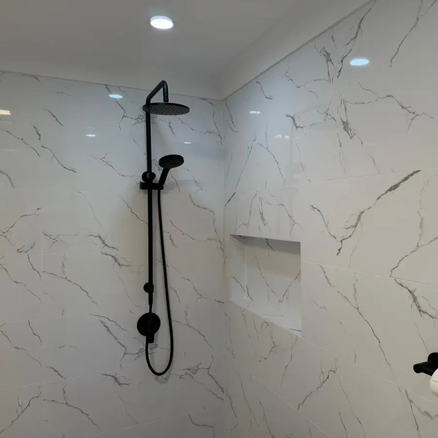 Matte black rain shower and handheld rail beside a tiled recessed shelf in the renovated Katoomba bathroom